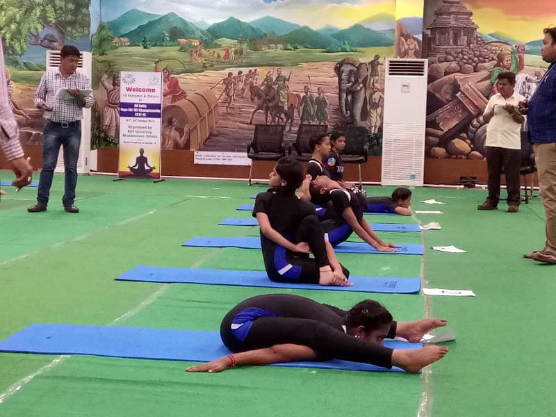 Advaitha Yoga students demonstrating advanced competition asanas including Kurmasana (tortoise pose) and Ardha Matsyendrasana before judges at KIIT championship