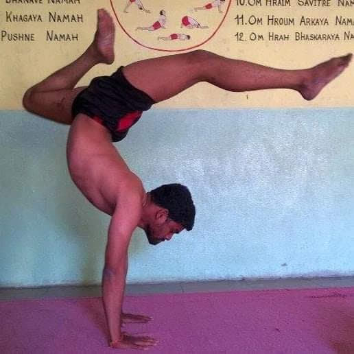 Advanced yogi performing Vrischikasana / Handstand Scorpion backbend pose demonstrating arm balance and spinal flexibility during Advaitha Yoga competition coaching